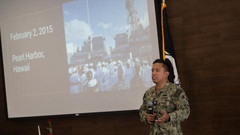 Josue “Alex” Ramos, Navy veteran and former Veterans Affairs work-study student at Holyoke Community College, speaking at Veterans Day at Westfield State. A projector behind him is showing a photo from Pearl Harbor, 2015.