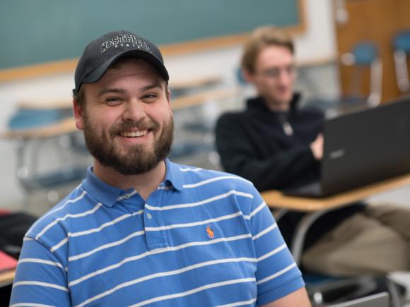 Male student, in ball cap, smiling at the camera