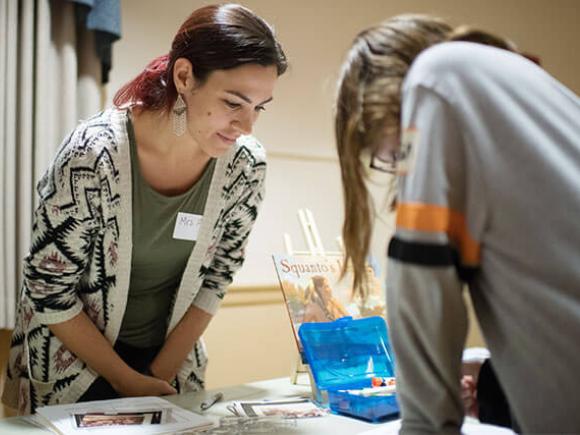 A Westfield University student watches a school-age student draws a picture.