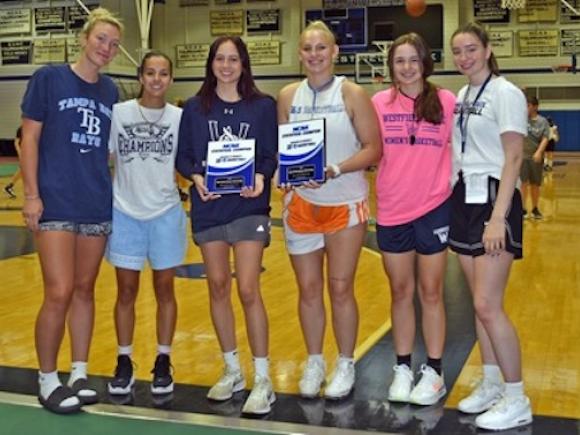 Several members of the women's basketball team stand next to each other and pose.