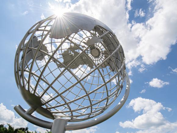 A close-up shot of the campus globe, backlit by a cloudy, blue sky.