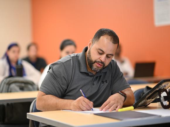 ABA graduate student writing notes in a classroom.