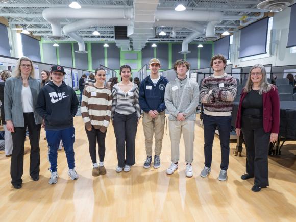 Students and faculty smiling at undergraduate research event.