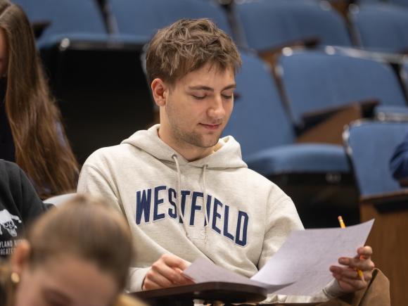 Student looking at a piece of paper holding a pencil wearing a WSU sweatshirt.