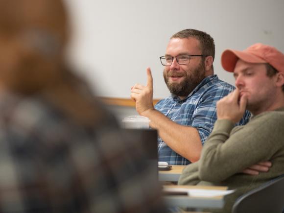 Student in classroom raises their hand.