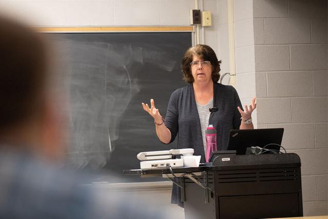 Professor lecturing at front of classroom.