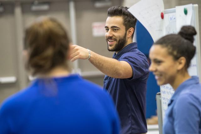 Sports medicine program students smile while talking to each other in a classroom.