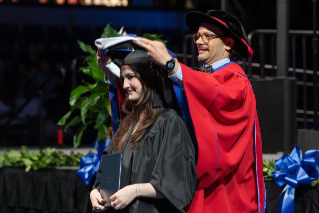 Faculty member and a student at commencement ceremony.