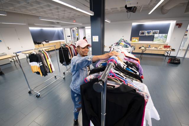 Campus thrift store with a student smiling at a clothing rack.