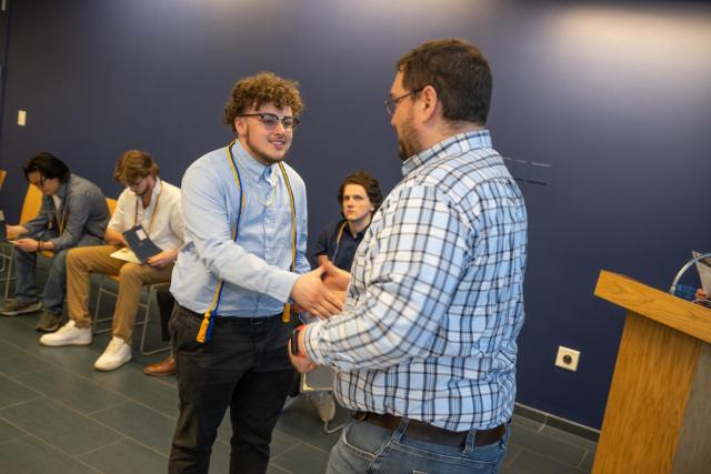 Student shaking hands with faculty member during the Economics Department Honors ceremony.