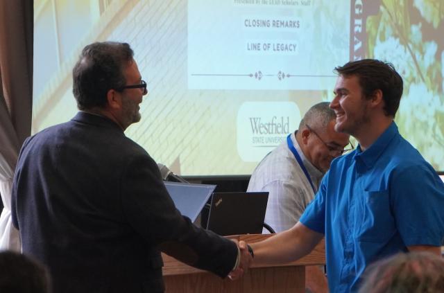 Student and faculty member shaking hands at a campus event.