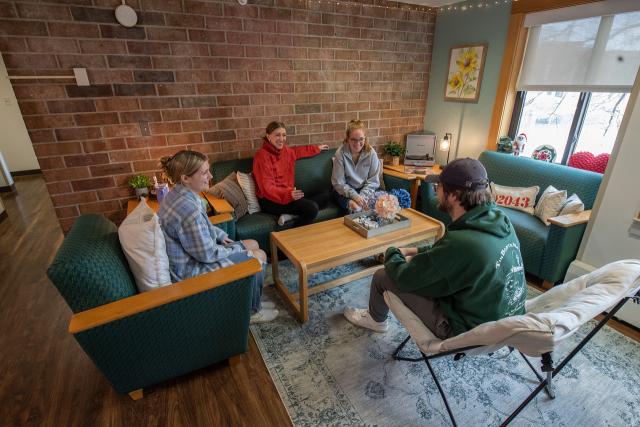 A group of students relaxing and talking around a couch in Conlin Hall.