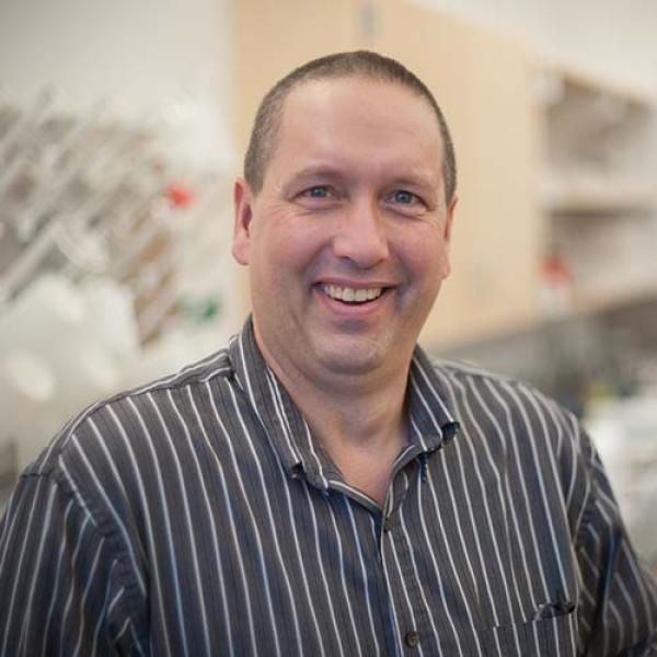 Dr. John McDonald, Chair of the Environmental Science Department at Westfield State University, smiles while standing in a science lab.