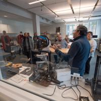 Faculty and staff gather at the RIDE Center as part of a two-day workshop on the new technology. They gather around a laser printer, 3D printer, and various other tools that will help enhance classroom work.